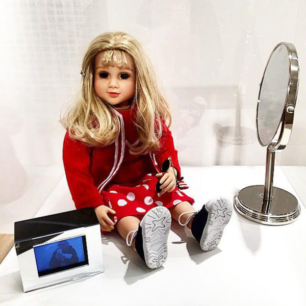 Lynn Hershman Leeson, CybeRoberta. Custom-made doll, clothing, glasses, webcam, surveillance camera, mirror, original programming and telerobotic head rotating system. 1996.